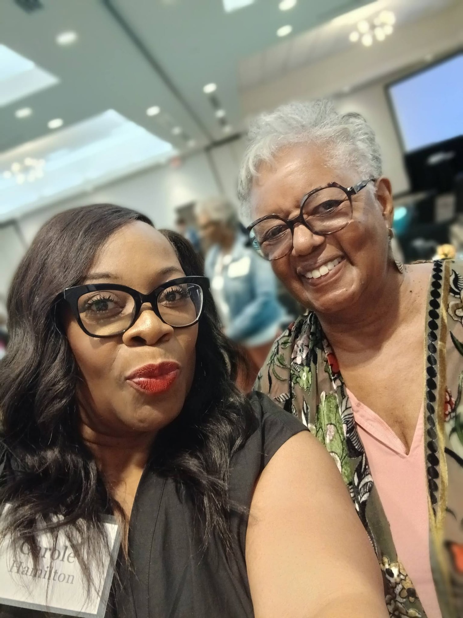 Two women smiling together at a past Be1 Experience